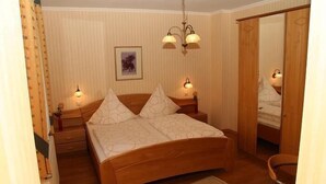 Ein Schlafzimmer mit einem Holzbett, zwei Nachttischlampen, einem gerahmten Bild an der Wand und einem Spiegel an der Tür.