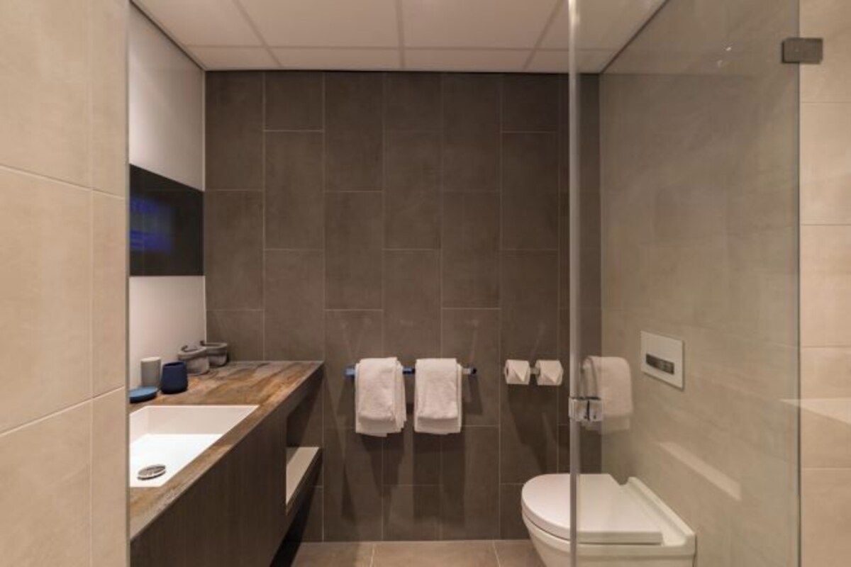 Une salle de bain moderne avec une douche à parois de verre, un meuble-lavabo en bois et des toilettes blanches.