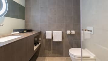 Une salle de bain moderne avec un grand lavabo, deux serviettes blanches, une douche en verre et des toilettes.