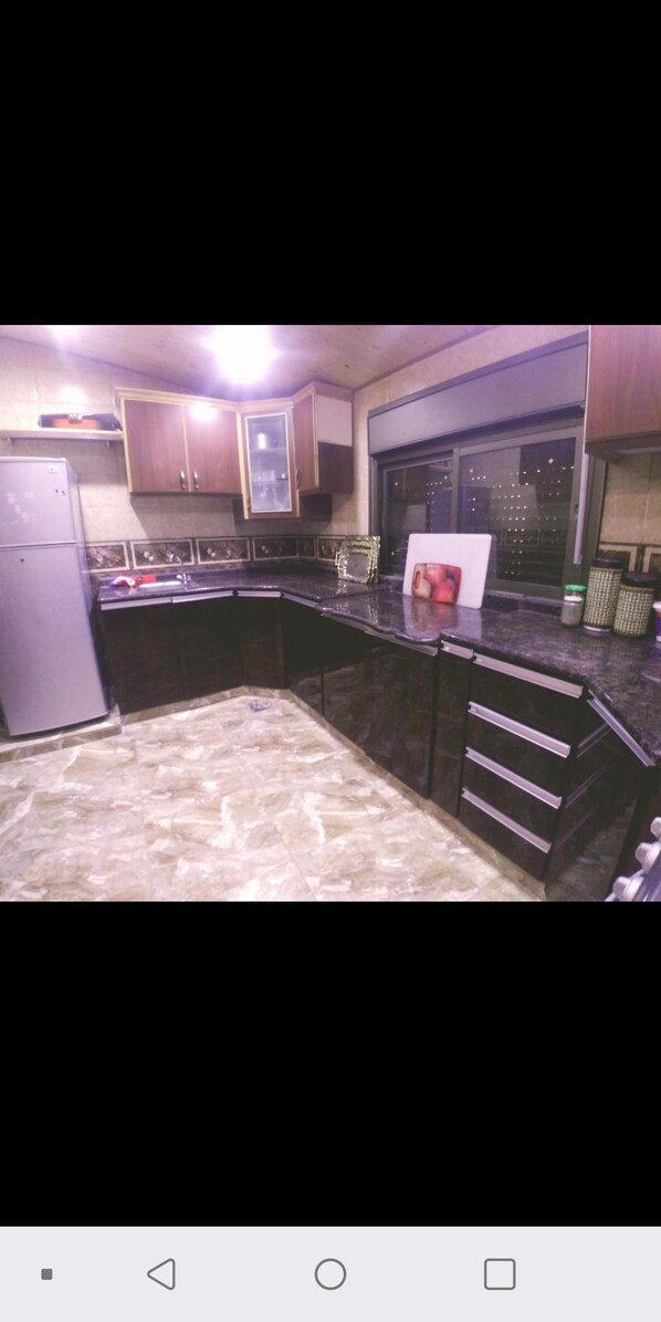 A kitchen with dark cabinets, a granite countertop, and a window with a city view.