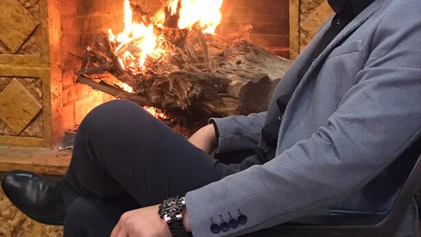 Una persona sentada frente a una chimenea encendida.