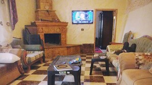 Una sala de estar con piso a cuadros, una chimenea, un televisor y un sofá.