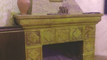 A stone fireplace with a green geometric pattern, a decorative vase, and framed artwork on the mantel.