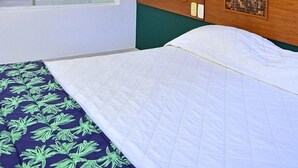 A hotel room with a large bed, a bathroom with a mirror, and a green wall with a leaf-patterned artwork. - Bella Ilha Pousada (Ilhabela)