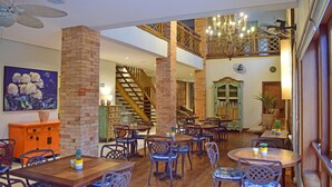 A spacious dining area with multiple tables and chairs, a staircase, and a chandelier. - Bella Ilha Pousada (Ilhabela)