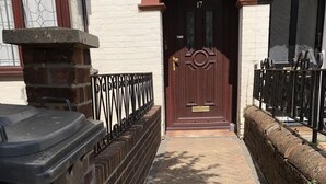 A paved pathway leading to a door with the number 17, flanked by brick walls and a metal fence. - 2 Bed Apartment in Basingstoke (Basingstoke)