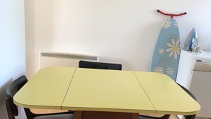 A dining table with four chairs, a radiator, and an ironing board with an iron in the background. - 2 Bed Apartment in Basingstoke (Basingstoke)
