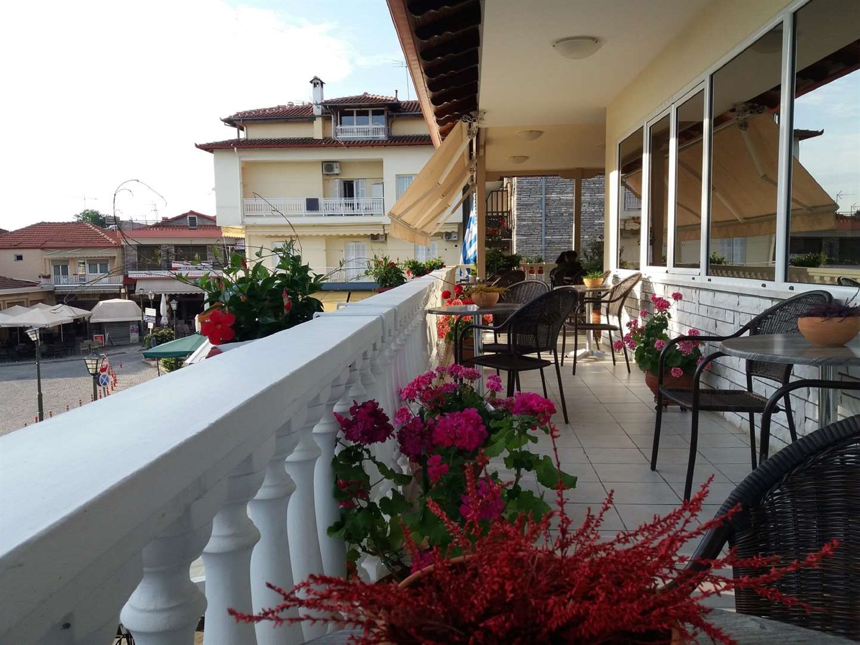 Un balcón con mobiliario exterior, plantas en macetas y vistas a edificios cercanos.