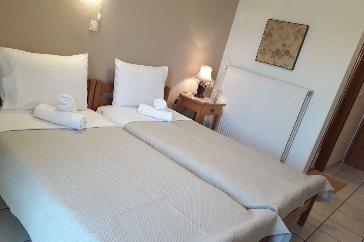 Ein Hotelzimmer mit zwei Betten, einem Nachttisch, einer Lampe und einer Heizung.