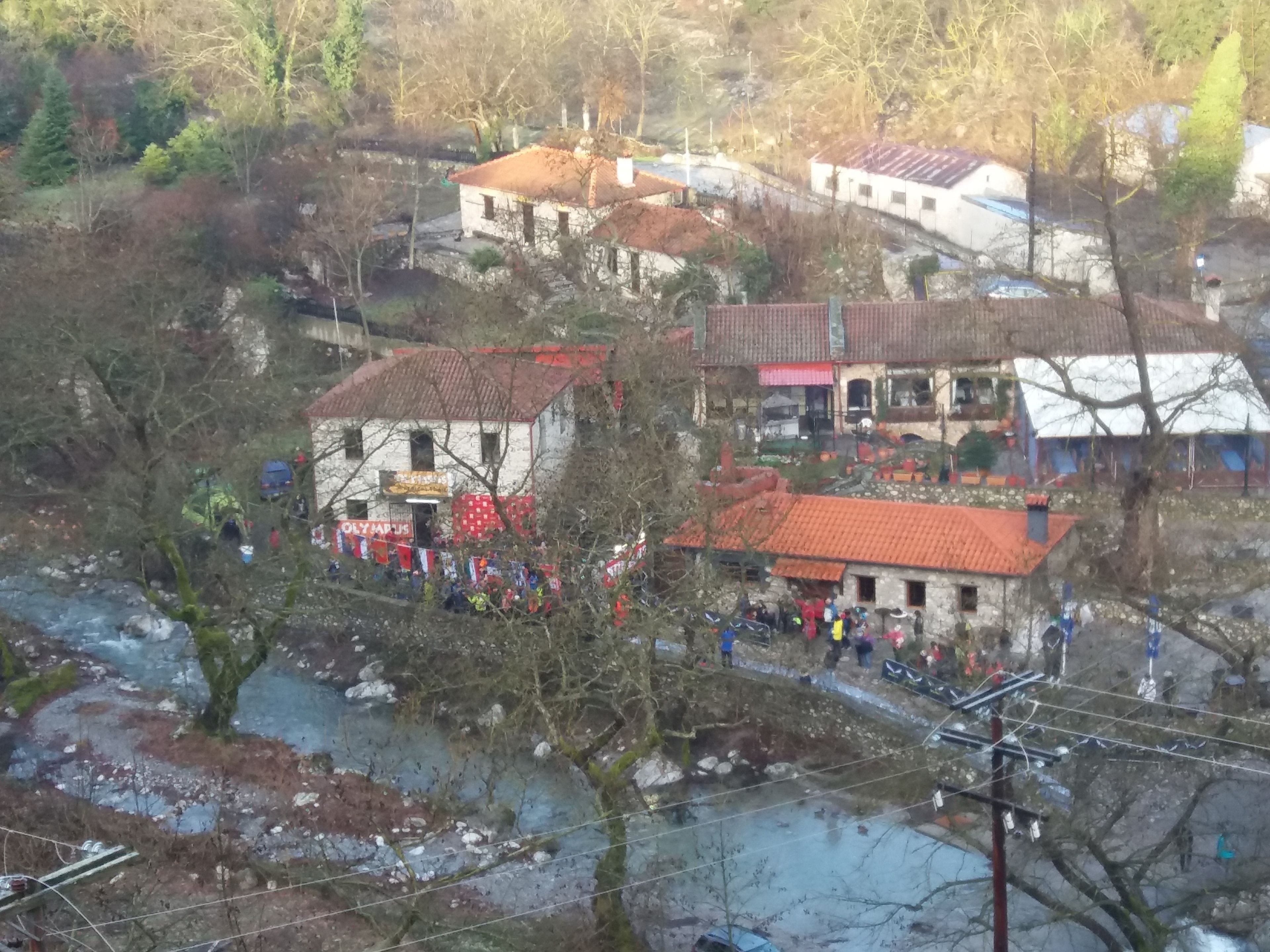 A rural village with traditional buildings, a river, and a small gathering of people.