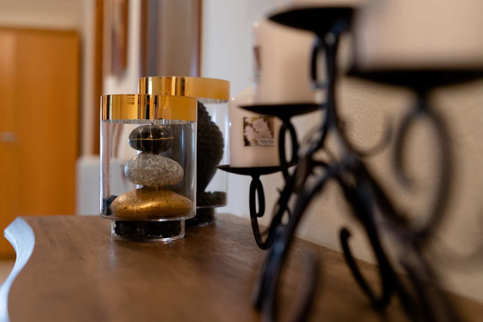 A wooden table with a glass container holding three stones and a candle.