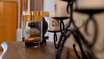 A wooden table with a glass container holding three stones and a candle.