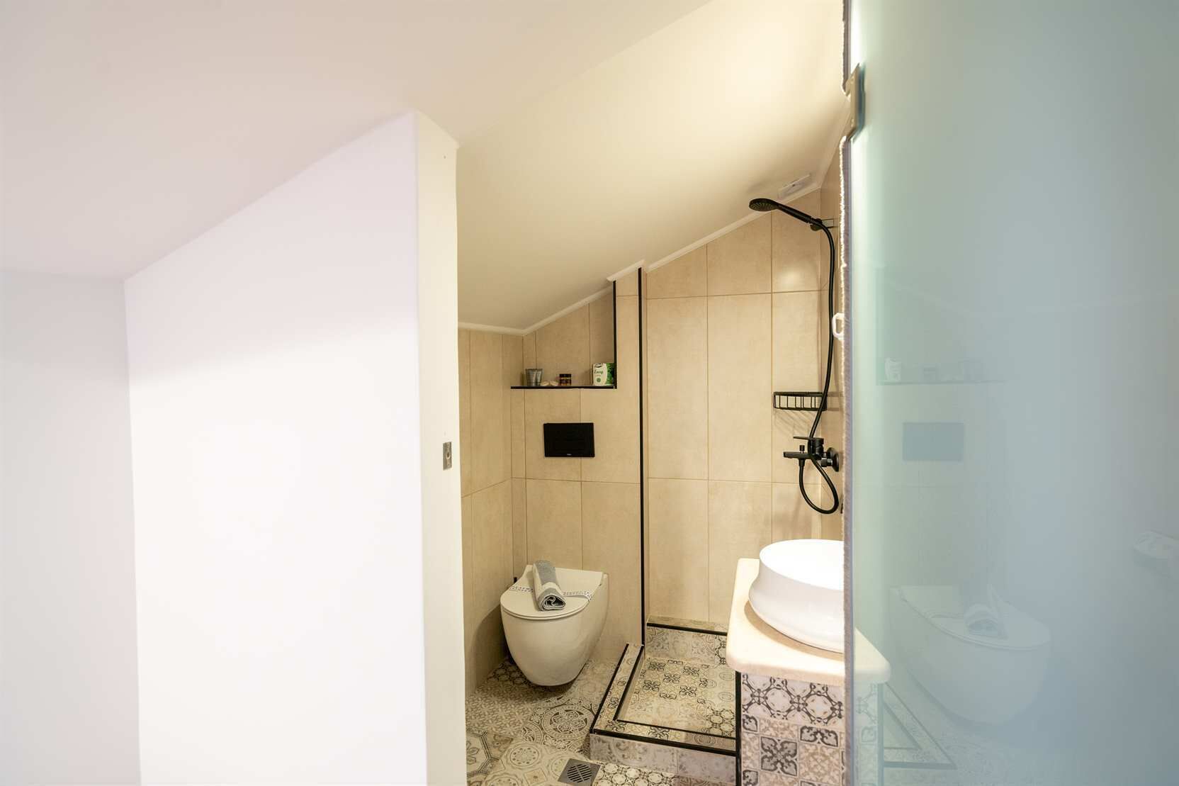 A modern bathroom with a toilet, shower, and sink.