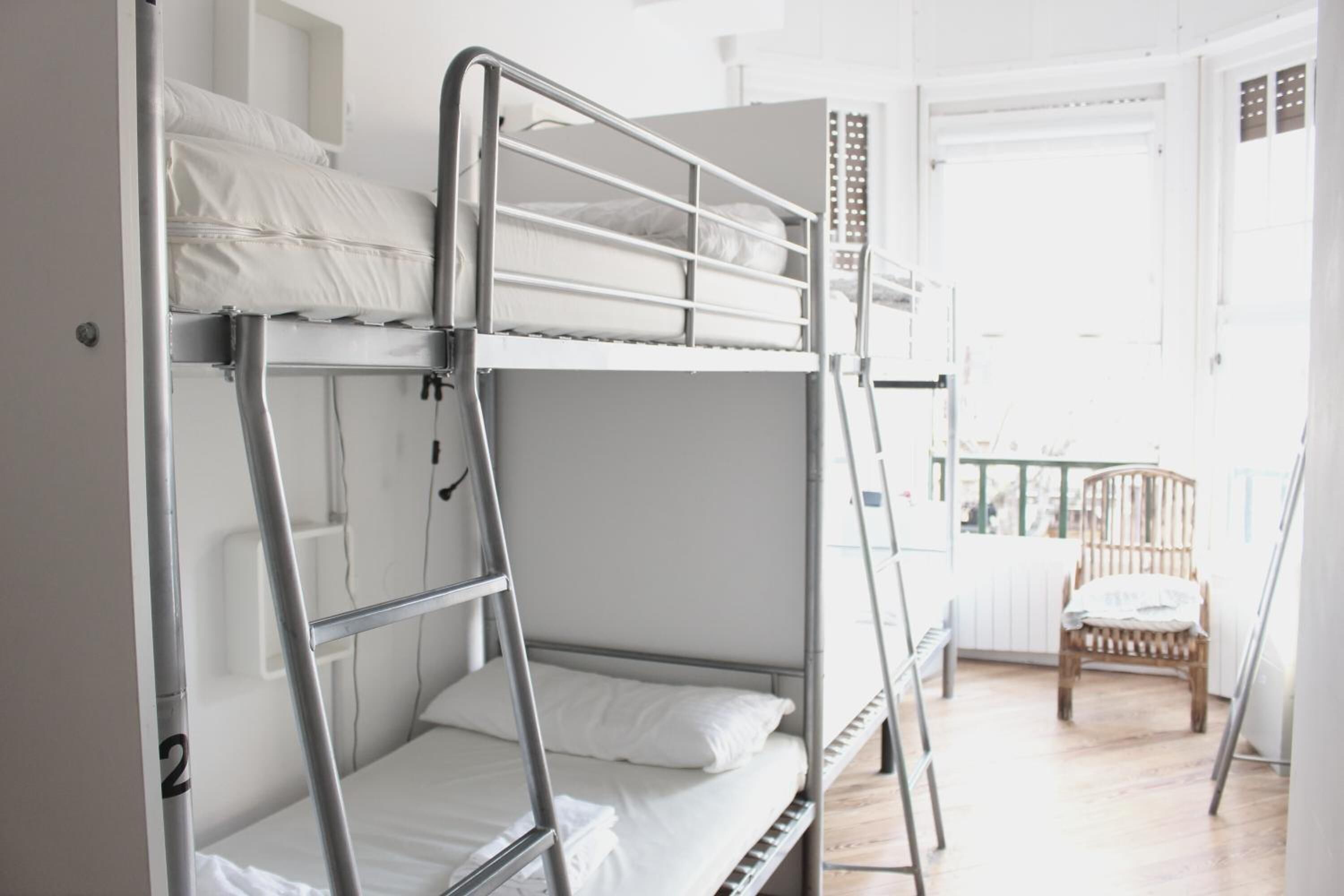 Camera con letto a castello, una sedia di legno e una porta bianca.