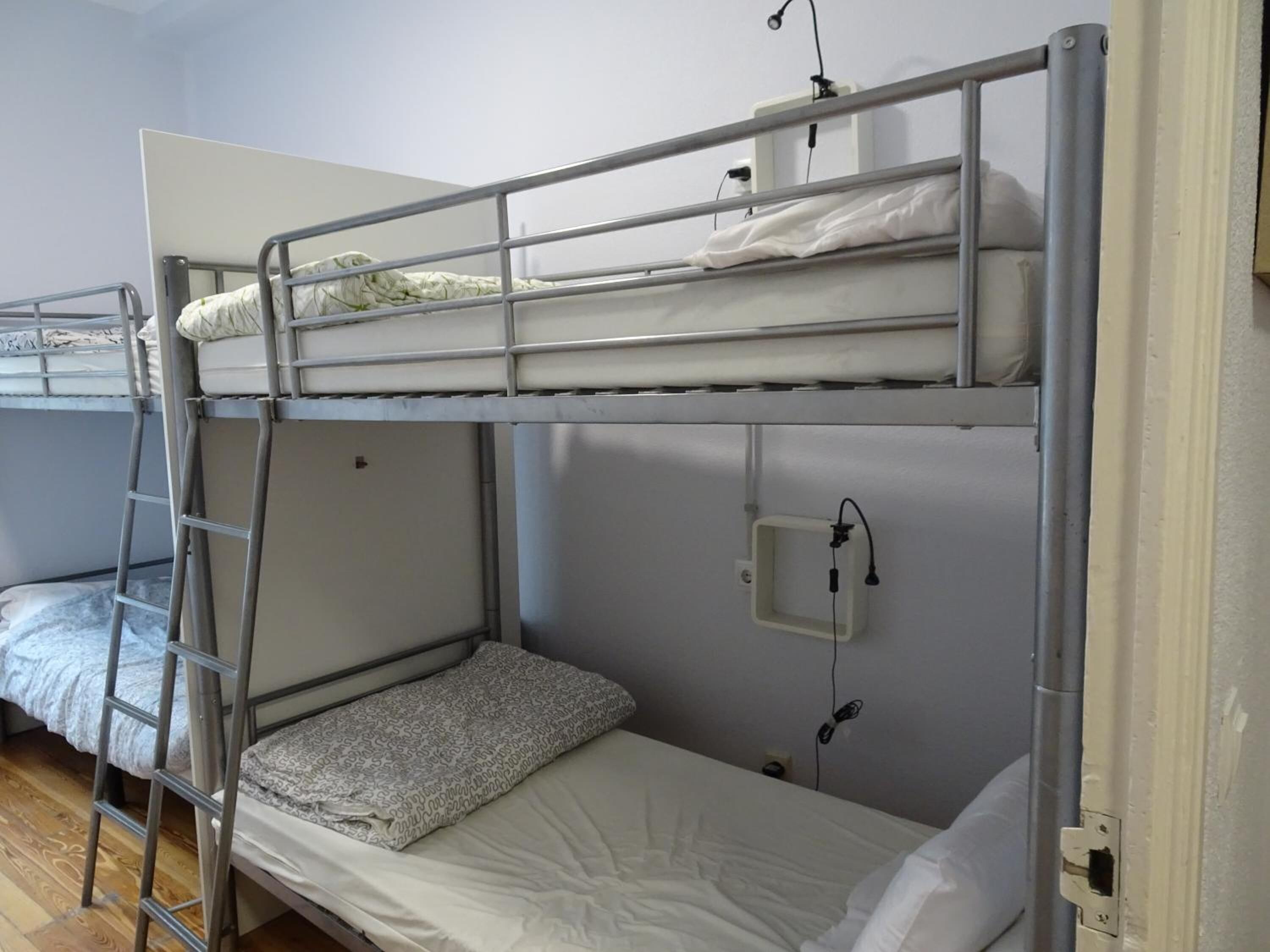 Habitación con literas, una escalera, un enchufe y una toma de corriente.