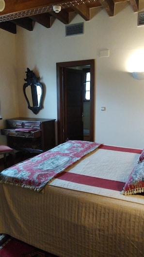 A room with a bed, a wooden dresser, a mirror, and a door.