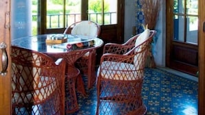 A room with a round table, wicker chairs, and large arched windows. - Hotel Palacete Real (Pilona)