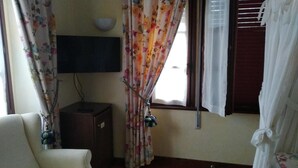 A room with a bed, a TV mounted on the wall, and curtains. - Hotel Palacete Real (Pilona)