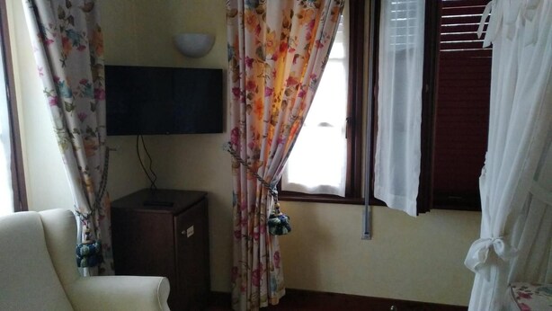 A room with a bed, a TV mounted on the wall, and curtains. - Hotel Palacete Real (Pilona)