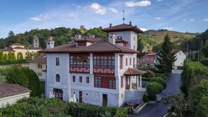 A white building with red accents, a stone facade, and a central tower. - Hotel Palacete Real (Pilona)