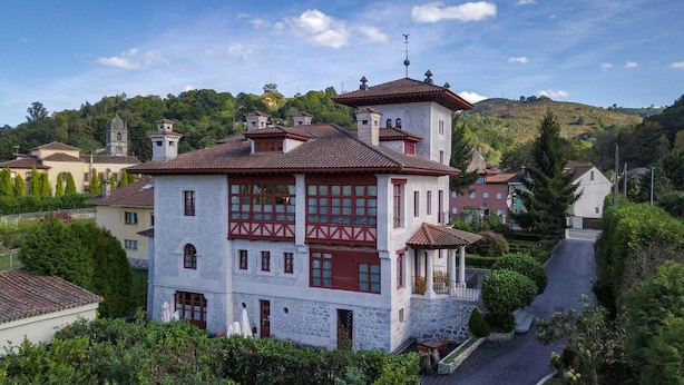A white building with red accents, a stone facade, and a central tower. - Hotel Palacete Real (Pilona)