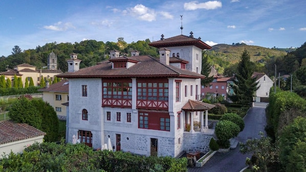 Un edificio blanco con detalles rojos, fachada de piedra y una torre central.