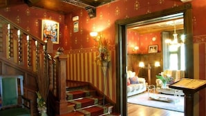 A grand staircase with ornate railings, a wooden floor, and a chandelier. - Hotel Palacete Real (Pilona)