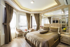 A modern hotel room with a large bed, a sitting area with a chair and a small table, a mirror, and a TV. - İstanbul Center Hotel (Istanbul)