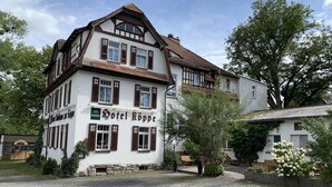 Een klassiek tweelaags gebouw met een bord waarop 'Hotel Kuppe' staat.