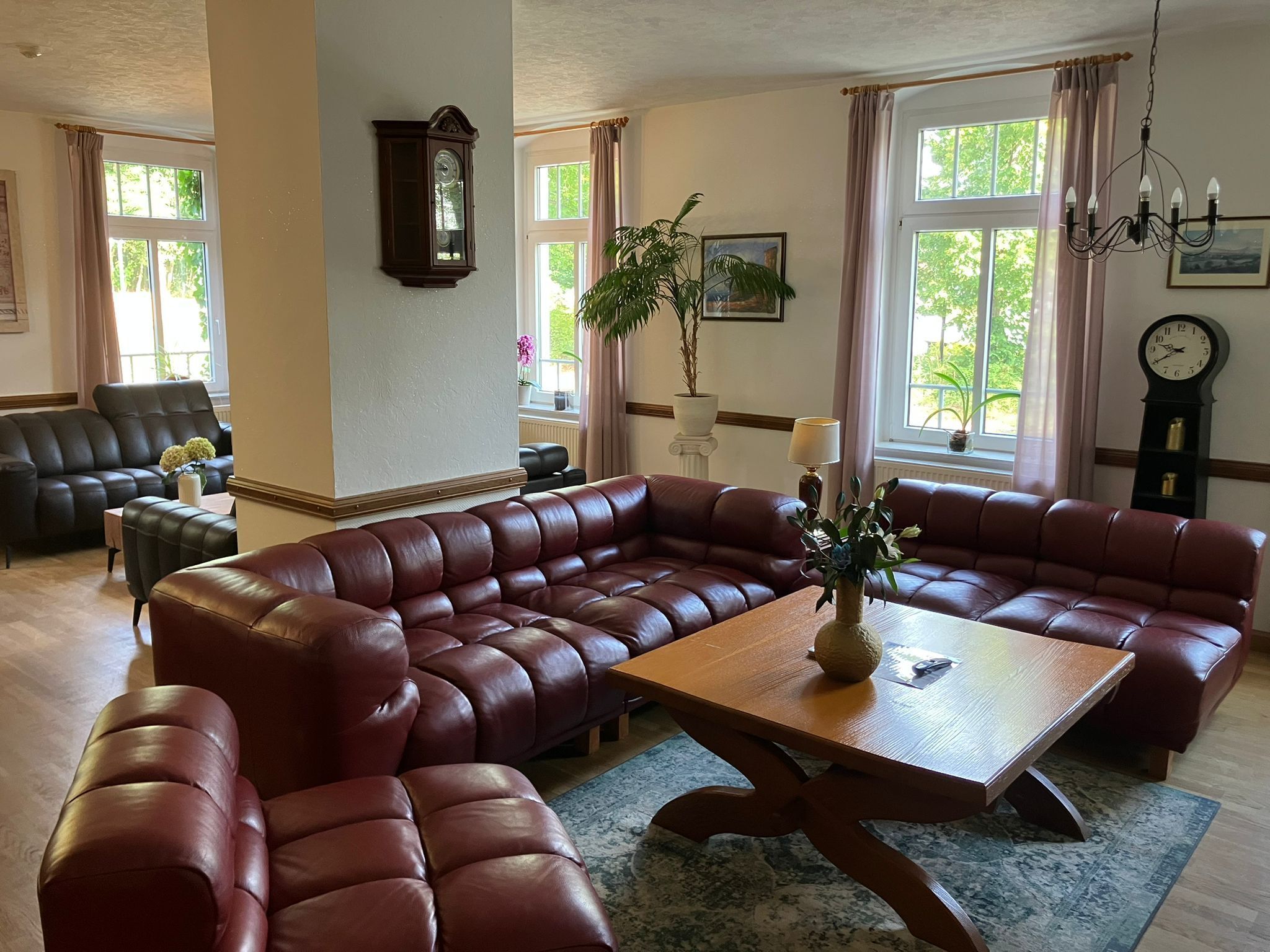 A living room with a large L-shaped sectional sofa, a wooden coffee table, and a chandelier.