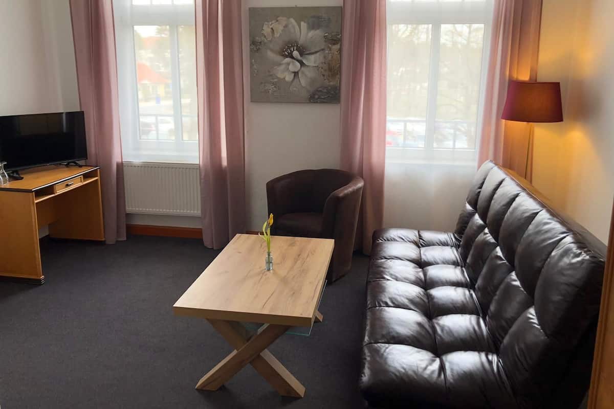 Uma sala de estar moderna com uma escrivaninha de madeira, um sofá de couro e um quadro na parede.