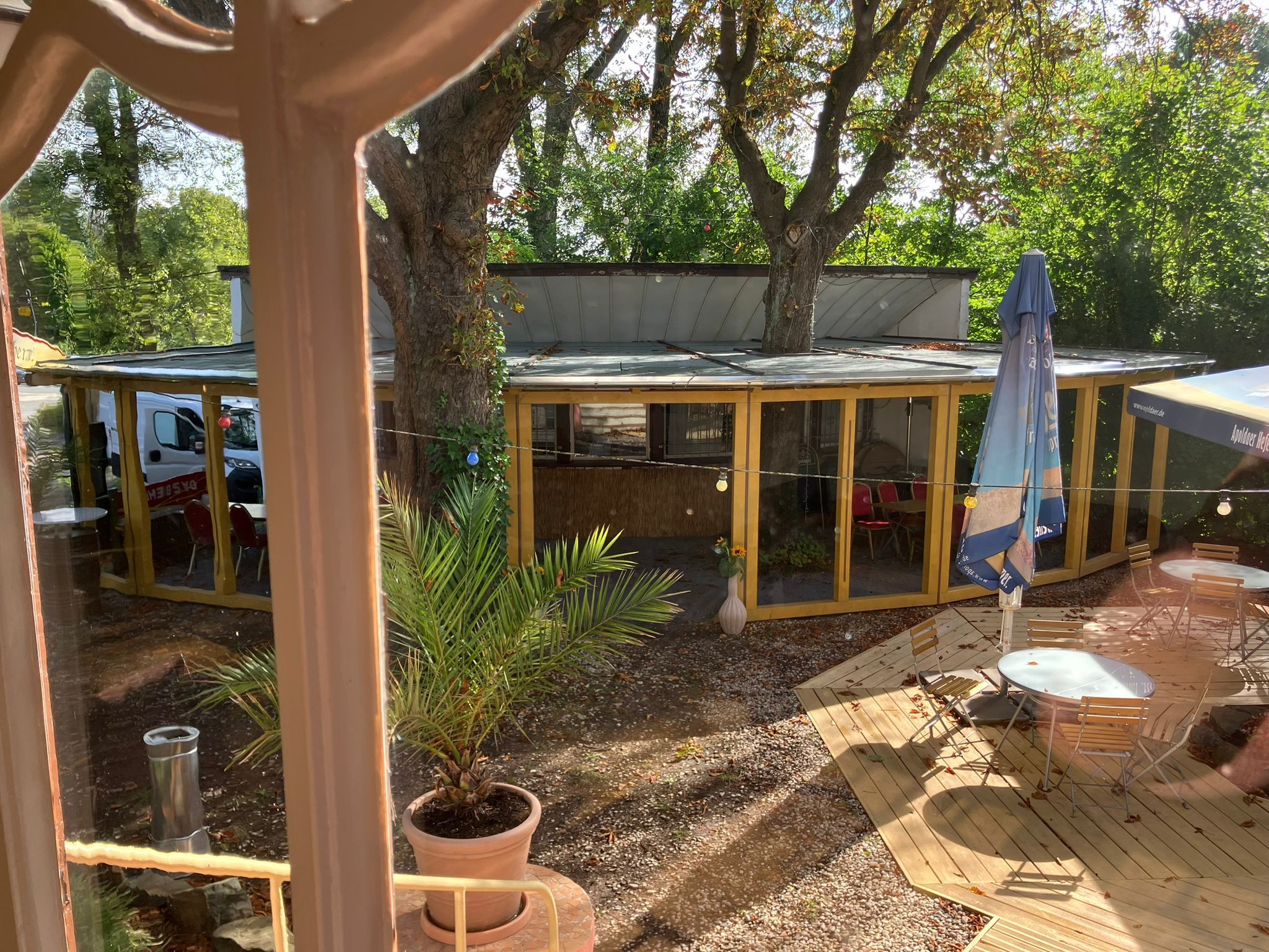 An outdoor patio area with a glass enclosure, wooden deck, and seating.