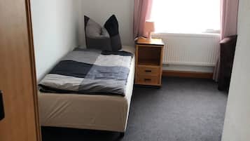 A bedroom with a bed, a nightstand, a lamp, and a window with curtains.