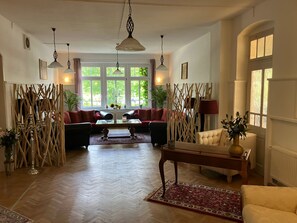 A spacious living room with a sofa set, a coffee table, and a decorative lamp. - Hotel Zur Köppe (Bad Klosterlausnitz)