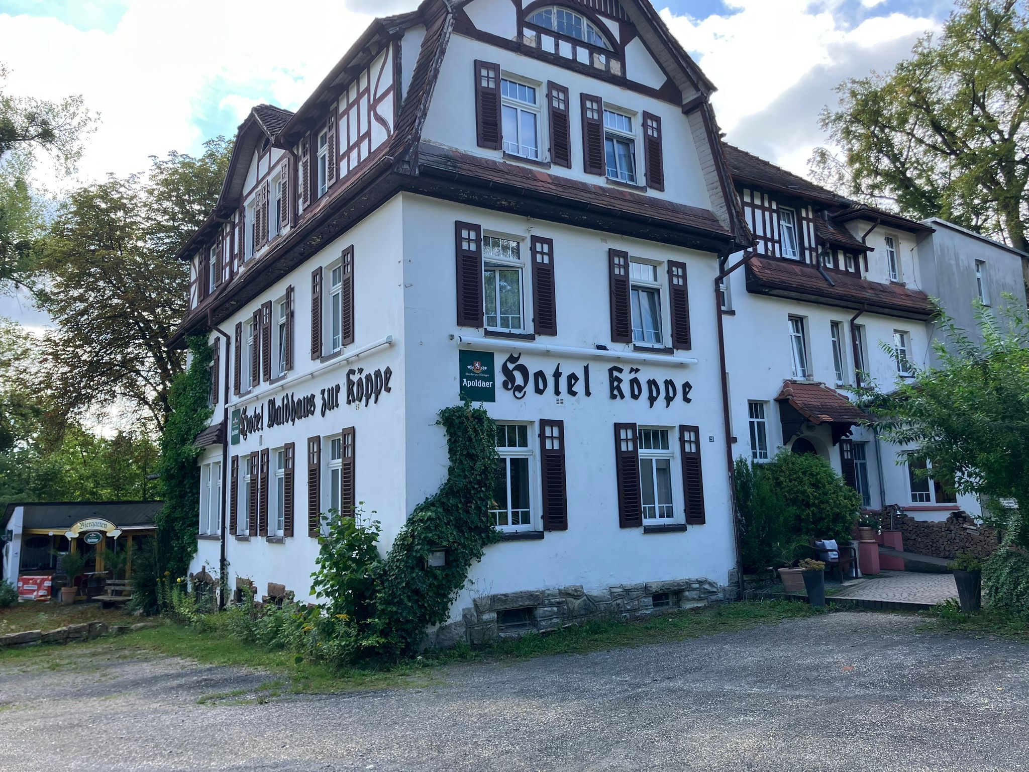 Un hotel tradicional europeo con fachada blanca y contraventanas de madera oscura, con un letrero que dice 'Hotel Kopp' y 'Biergarten'.