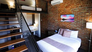 A room with a bunk bed, a desk, a chair, a bed with pillows, and a painting on the wall. - The Hotel Sturgis (Sturgis)