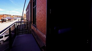 A narrow outdoor corridor with a metal railing, a brick building on one side, and a clear sky. - The Hotel Sturgis (Sturgis)