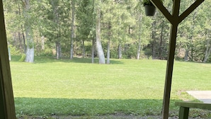 A view from a covered porch with a concrete floor and a wooden railing.