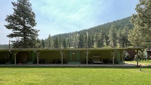 A lodge with a covered porch, outdoor seating, and a view of a forested hillside.