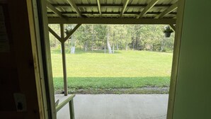 A doorway leading to an outdoor area with a concrete floor and a grassy lawn.
