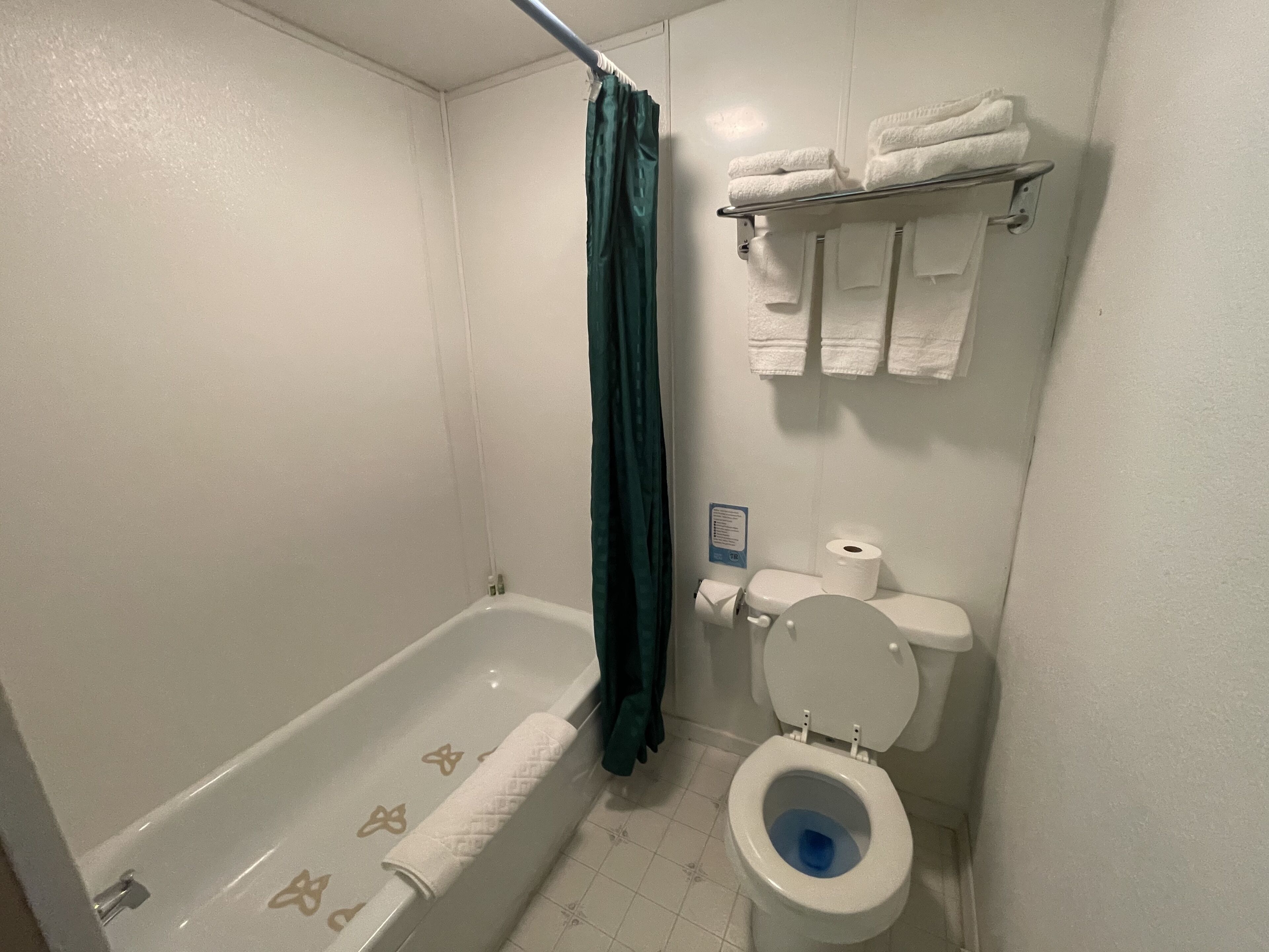 A bathroom with a bathtub, toilet, and a towel rack.