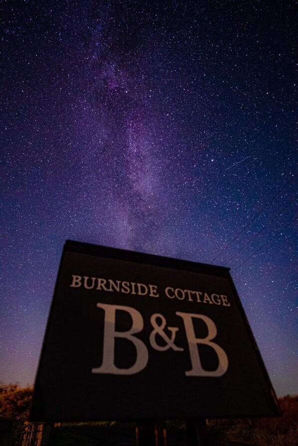 A sign for Burnside Cottage with a B&B logo against a starry night sky.
