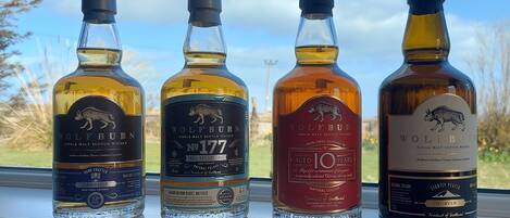 Four bottles of whisky on a windowsill with a scenic view.
