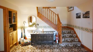 A staircase with floral patterned carpet, a wooden handrail, and a wall-mounted mirror. - Scourie Lodge B&B and Gardens (Scourie)