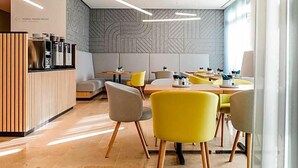 A modern restaurant interior with a reception desk, seating area, and patterned wall. - Art Hotel Ahlen (Ahlen)