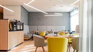 A modern restaurant interior with a reception desk, seating area, and patterned wall. - Art Hotel Ahlen (Ahlen)