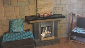 A stone-walled room with a fireplace, a sofa, and a chair.