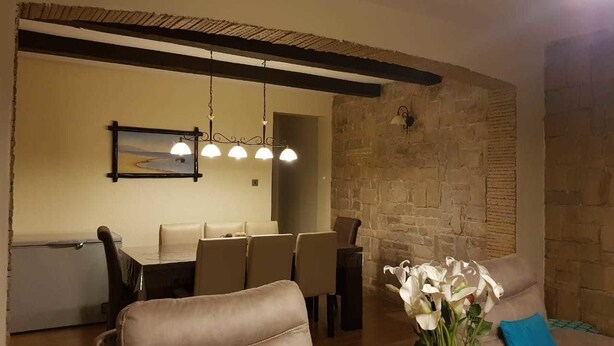 A dining area with a stone wall, a table with chairs, and a hanging light fixture.