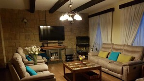 A cozy living room with a fireplace, a flat-screen TV, and comfortable seating.