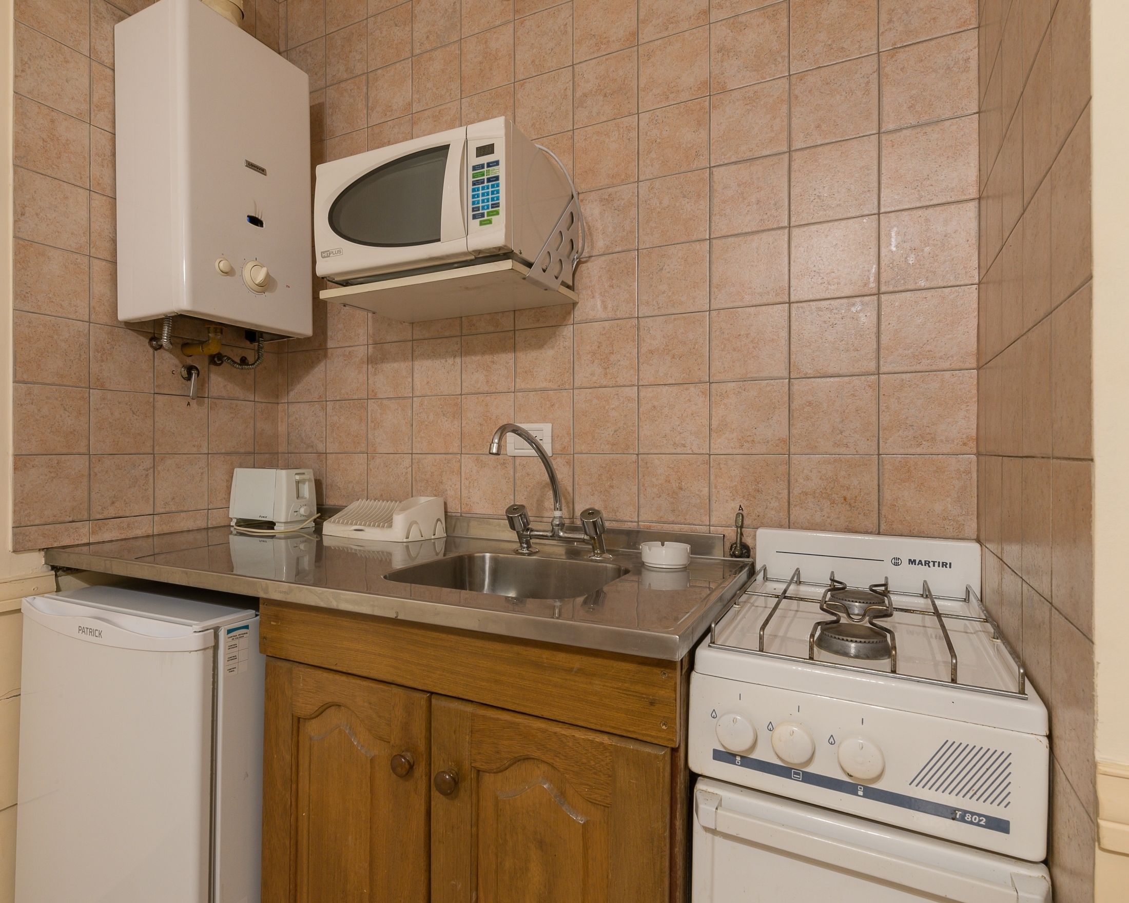 Una cocina equipada con microondas, pileta y cocina a gas.